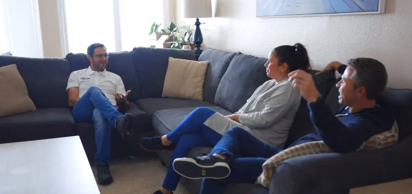 Clients meeting on a gray sectional sofa in a bright remodeled living room