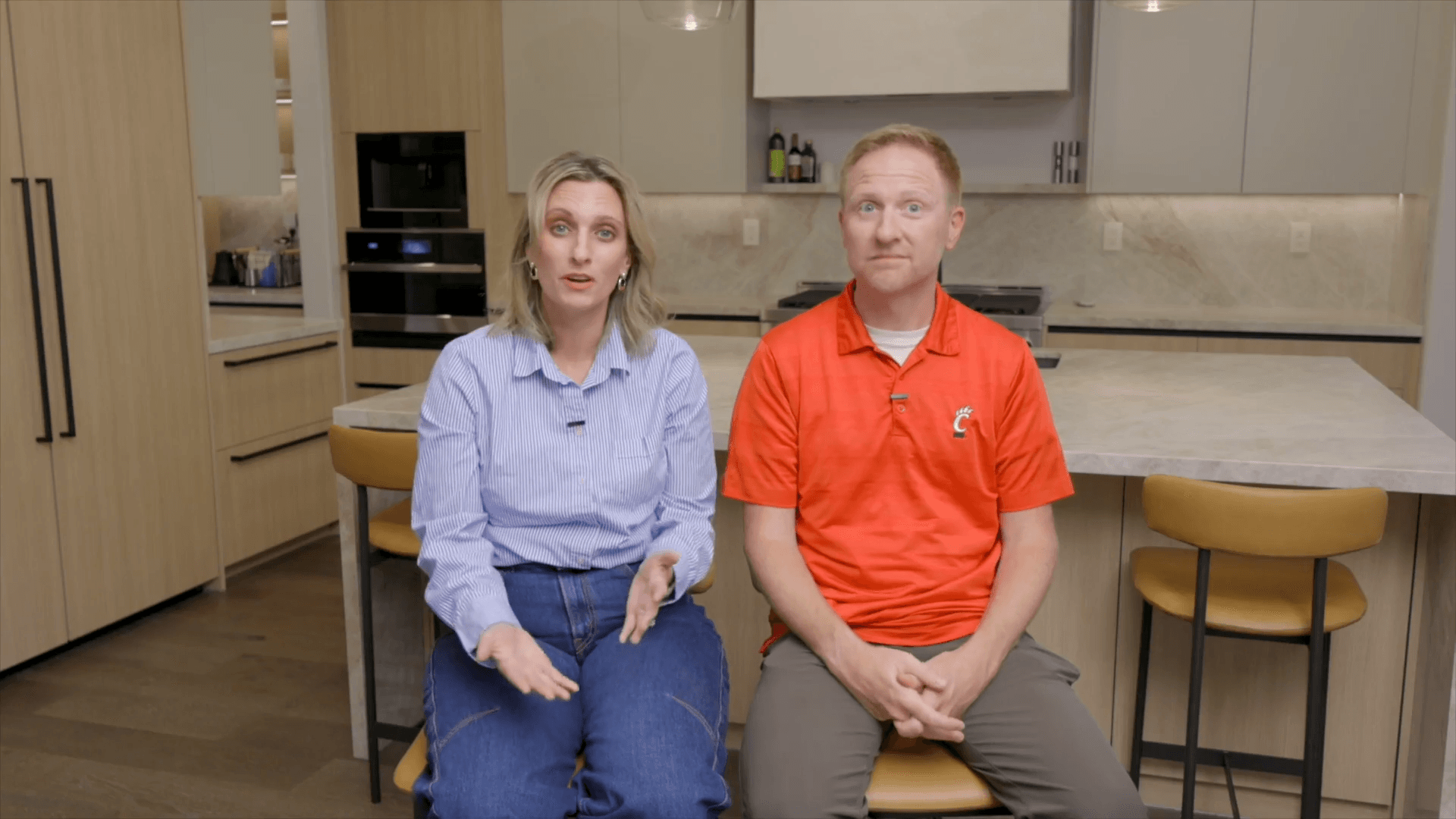 Couple seated in a remodeled kitchen with light wood cabinetry and stone countertops