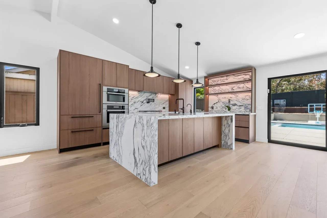 Modern kitchen remodel with walnut cabinets and book-matched marble waterfall island