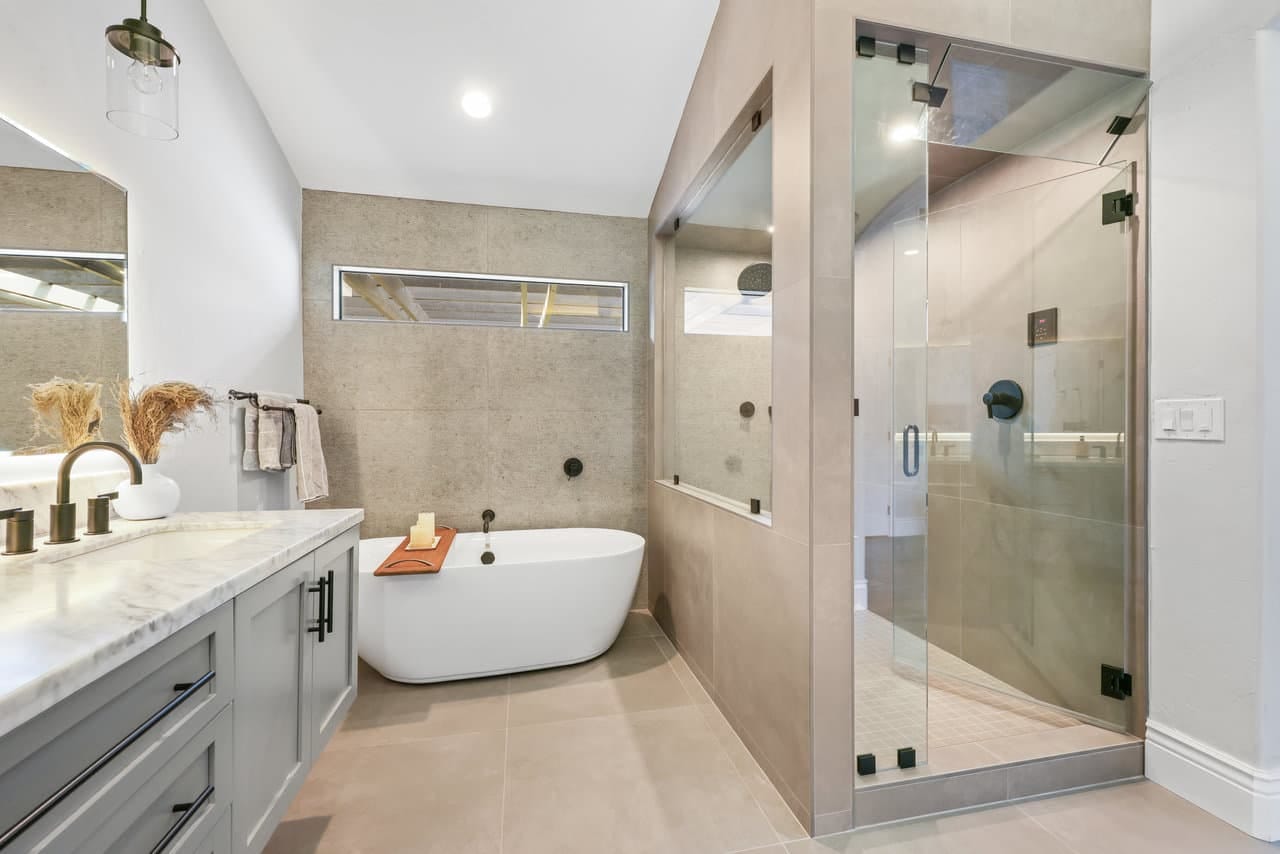 Primary bathroom with freestanding tub, glass walk-in shower and marble-topped gray vanity