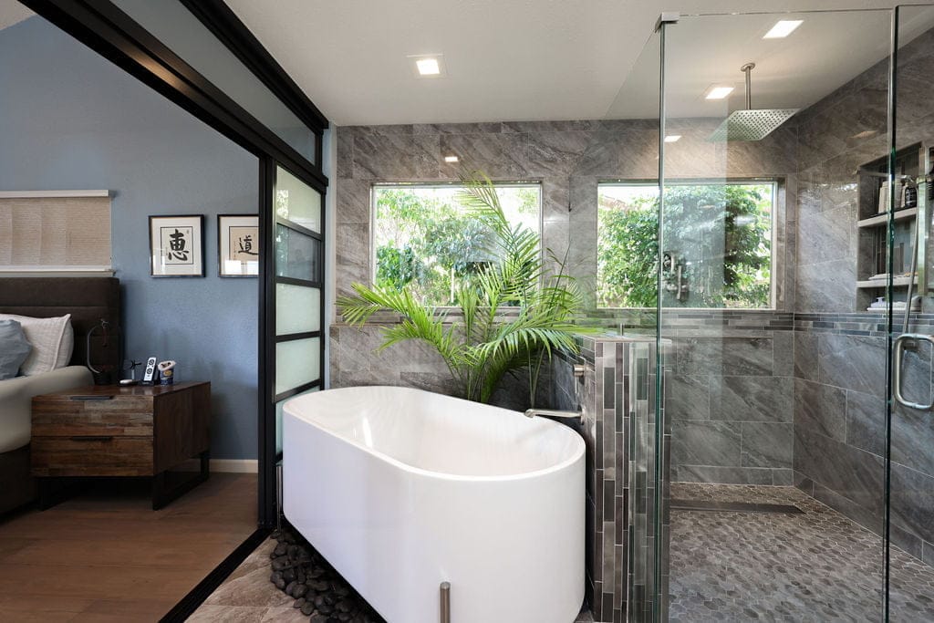 spa primary bath with freestanding tub, glass shower and stone accent wall by window