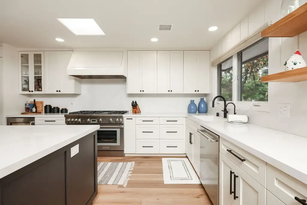 Open kitchen with two-tone cabinets, white quartz counters and floating wood shelves