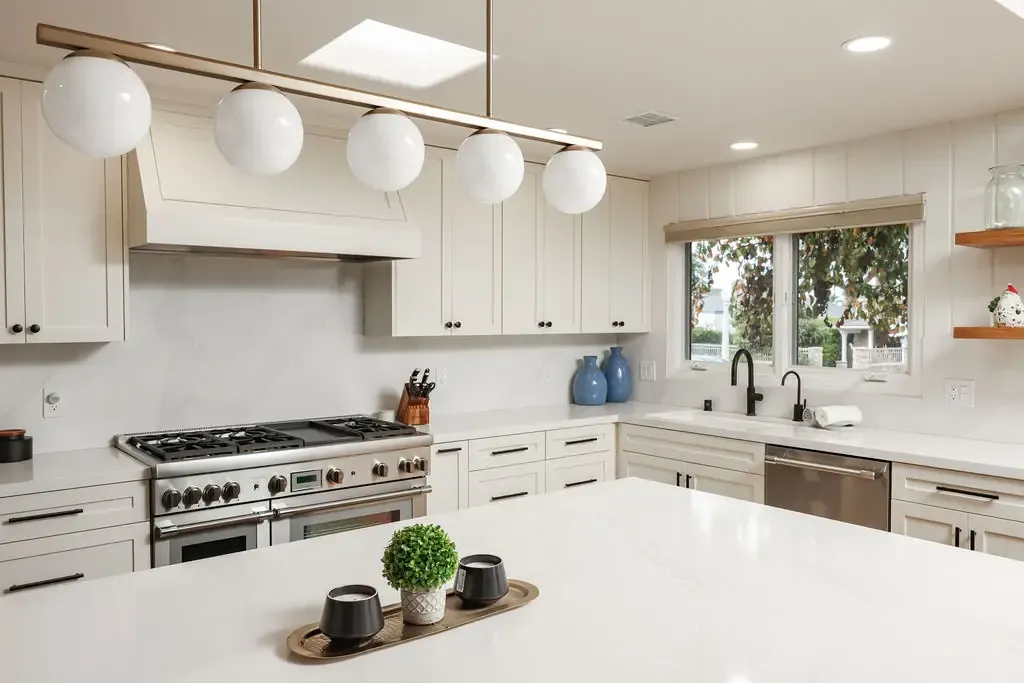 Spacious kitchen with white range hood, quartz island and stainless professional range